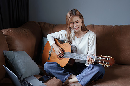 在沙发上弹吉他 度假时放松压力的年轻亚洲女人的肖像职业原声青少年家庭生活媒体互联网摄影手指演员指板图片
