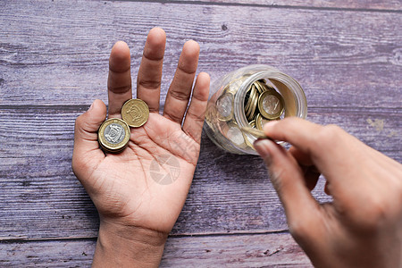 年轻男子在白色的罐子里存着硬币d手指贷款金融经济投资预算银行业男人退休财富图片
