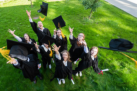 穿着毕业礼服的同学们丢掉帽子 从上面看学习证书学校快乐团体研究生天空仪式长袍团队图片