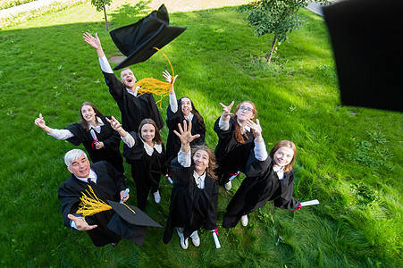 穿着毕业礼服的同学们丢掉帽子 从上面看空气友谊学生团队教育中学快乐文凭团体女性图片