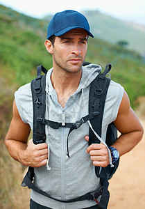英俊的年轻徒步旅行者背着一个背包看侧面 看着他的背部图片