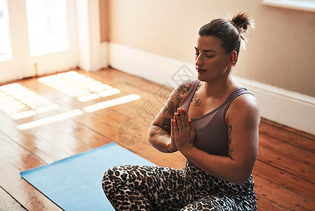 一位年轻女性在家里的瑜伽垫子上冥想 这为学习如何放手提供了一种方法图片