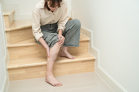 亚裔女性触摸和感到痛苦 她的膝盖在楼梯上 在家中 健康的医学概念症状跑步压力办公室医院女士肌肉伤害解剖学药品图片