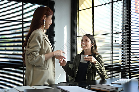 两个微笑着的女商务人士聊天 在现代办公室咖啡休息期间讨论团队项目 研讨会图片