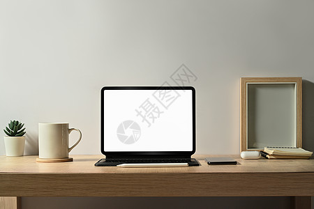使用平板 图片框 咖啡杯和木制桌上的家用植物的舒适工作场所 您的广告屏幕空白图片