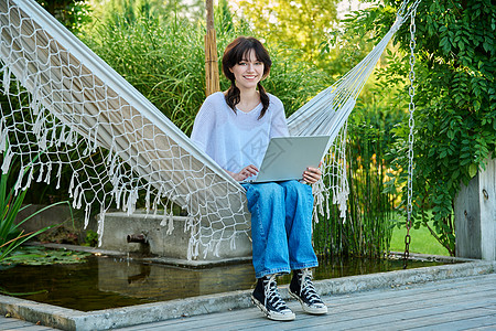 利用笔记本电脑进行休闲学习 在吊床上放松的少女学生女孩休息快乐大学青年闲暇成人教育互联网图片