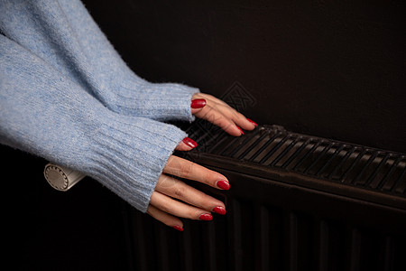 女人的冷手放在房间里的热散热器上用户持有暖手热能测量手指季节控制消费者生态图片