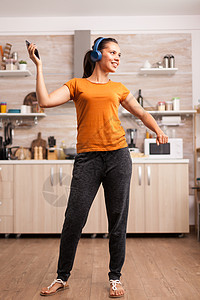 厨房的节能舞蹈唱歌喜悦歌曲舞蹈家娱乐女性耳机享受公寓运动图片
