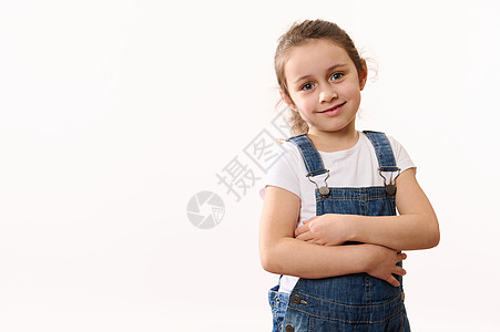穿着牛仔服的可爱女婴 拥抱自己 笑笑牙笑笑看着相机 孤立在白色背景上图片