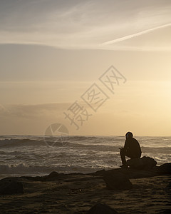 海洋球日落时 在海边海滩上带着耳机坐着男孩的休眠 亚洲帅哥20多岁就当模特儿了背景