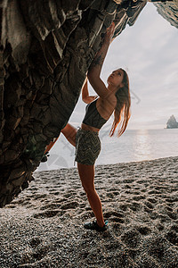 攀登岩石的体育妇女 身材苗条的年轻女子在火山玄武岩洞穴中攀爬 欣赏美丽的海景 女运动员在大自然中训练 女人克服困难的攀登路线风险图片
