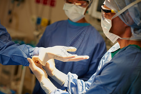 在手术准备中互相帮助 外科医生戴上手术手套准备手术图片