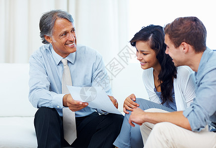 夫妇与理财规划师讨论 成熟的顾问向家里的年轻夫妇展示财务计划图片