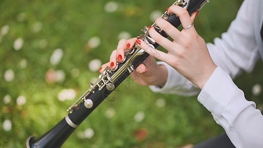 一个女孩夏天在公园里弹单簧管 手贴紧一点 举起手来独奏艺术家天赋女孩合奏娱乐女士演奏家孩子旋律图片