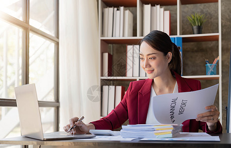 微笑的年轻女性在办公室和平板电脑上看工作商业文件背景图片