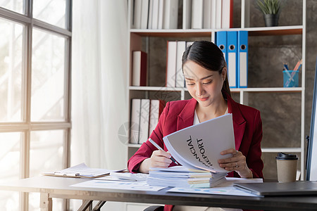 亚洲女商务人士早上一大早穿西装 赶着去清理办公室的商务文件呢?背景图片