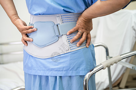 穿背止痛带的亚洲女病人 用助行器换整形腰椎脊柱药品骨科关节炎矫正疾病肌肉绷带支撑姿势图片