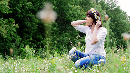 在一个森林里 一个年轻女子 一个黑发女人编织着一朵香米花圈图片