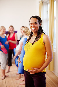 享受健康的孕期生活方式 一位快乐的年轻非洲裔美国孕妇和她的朋友站在健身房里 手拿运动垫图片