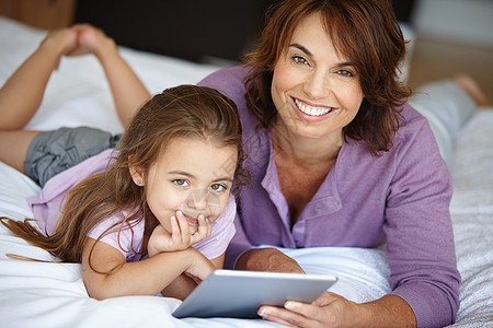 母亲和女儿在家里一起使用数字平板电脑 教她如何学习科技 (笑声)图片