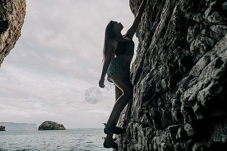 攀登岩石的体育妇女 身材苗条的年轻女子在火山玄武岩洞穴中攀爬 欣赏美丽的海景 女运动员在大自然中训练 女人克服困难的攀登路线运动图片