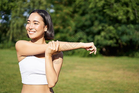 年轻健身女子伸展手臂的肖像 培训前的热身 公园体育活动 慢跑和排泄等运动活动瑜伽训练快乐女性日落跑步太阳慢跑者工作运动装图片