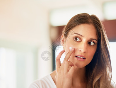 保护你健康皮肤的清洁 调子和润滑剂 一个年轻女性在脸上施温柔剂图片