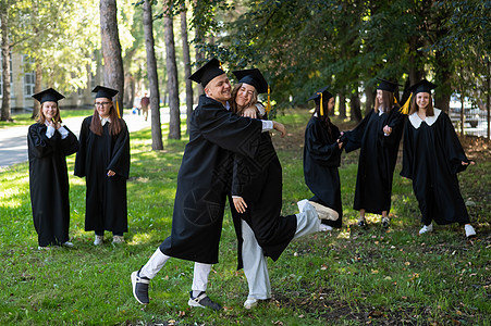 一群穿着长袍的毕业生祝贺对方在户外毕业 笑声朋友们学校女性女孩校园大学学习证书友谊乐趣图片