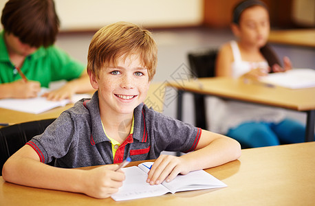 他最喜欢的科目 一个可爱的小男孩在课堂上做功课图片