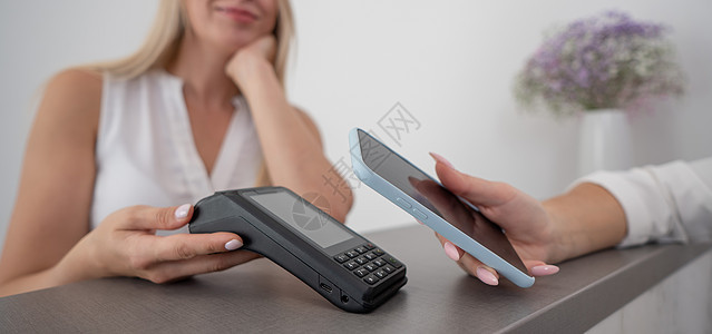 妇女使用智能手机使用的NFC非接触付款支付费用柜台金融零售近场银行业女性信用出纳员交易女孩图片