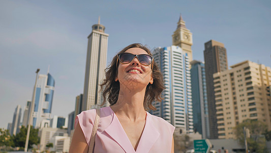 快乐的女孩在迪拜市中心走来走去 在摩天大楼的背景幸福技术旅游日落城市女士乐趣成人码头旅行图片