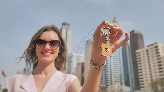 在迪拜摩天大楼的背景下 女孩拥有新房子的钥匙 校对 Portnoy经纪人合同商务男人代理人金属投资男性房东女士图片