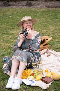 一个穿着长裙和草帽的年轻女子 正在吃水果野餐上休息动物宠物金发女郎闲暇季节幸福假期阳光短发女孩图片