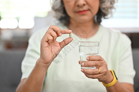 拥有避孕药和水杯的中年妇女 老年人保健 医药治疗概念 第12条疼痛客厅药片病人女士福利制药药店女性治愈图片