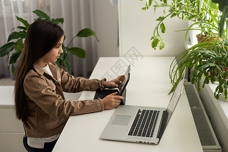 学校的少女学生戴着耳机在电脑屏幕上与在线老师进行远程学习 网络导师为青少年学生提供远程课堂教学 使他们可以在家进行在线学习 肩上图片