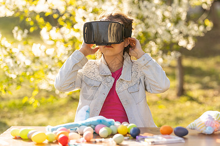 青少年玩家女孩戴着虚拟现实眼镜和耳机体验幻想世界 戴着虚拟眼镜的带复活节彩蛋的少女模拟器游戏创新风镜齿轮工具互联网粉色娱乐视频图片