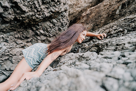 攀登岩石的体育妇女 身材苗条的年轻女子在火山玄武岩洞穴中攀爬 欣赏美丽的海景 女运动员在大自然中训练 女人克服困难的攀登路线悬崖图片