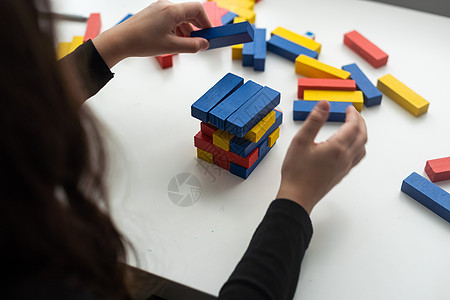 孩子们在操场上搭积木 小女孩玩堆叠木块 Jenga 游戏 进行冥想练习 手部运动控制培养计算技能儿童游戏概念幼儿园危险建筑物玩具图片