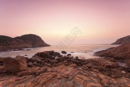 日出时沿海岸的海石图片