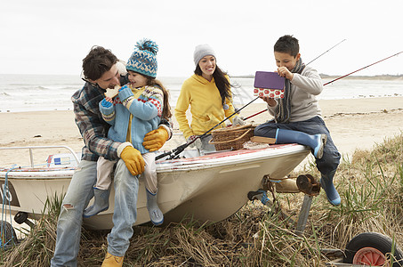 家庭小组在冬季海滩与钓鱼 Rod号船上坐船 女孩 孩子图片