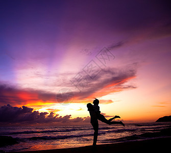 快乐的情侣拥抱海滩的休美月图片