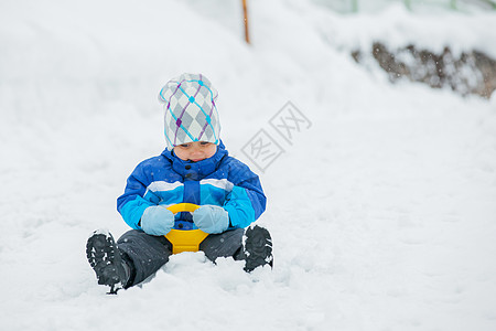 男孩在雪坡上兜风 兴奋 连指手套 假期 平底雪橇 速度 帽子图片