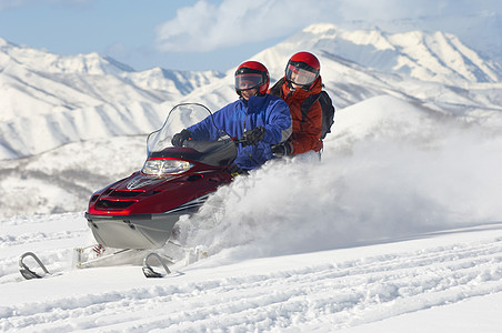 多族裔夫妇在雪上骑摩托车滑雪图片