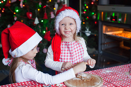小女孩在圣诞老人的帽子里为圣诞节烤姜饼 擀面杖图片