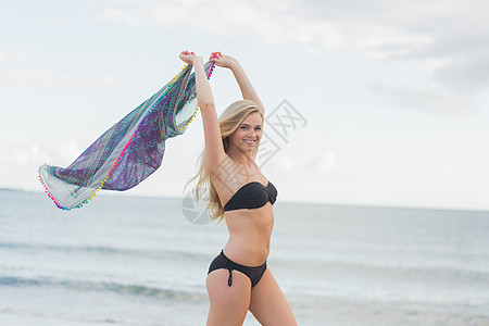 穿着比基尼的快乐女人 在海滩上拿着围巾图片
