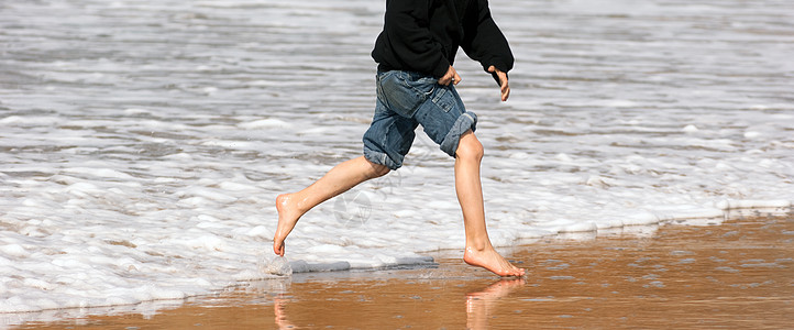 年轻男孩在脚踏足的海洋海滩冲浪撞碎海泡沫 海滨 海岸线图片