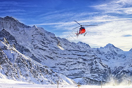 红直升机在Jungfrau山附近的swis alps上空飞行图片