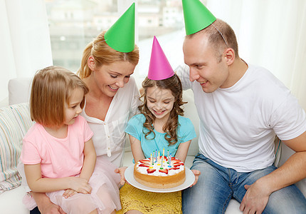 带着两个孩子的笑着家庭 戴着帽子和蛋糕的孩子 女孩们 母亲图片