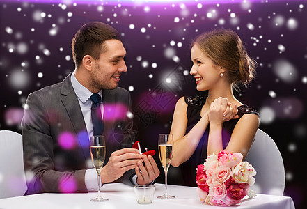 在餐厅微笑的夫妇与红色礼品盒 男人 情人节 订婚图片
