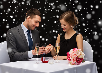 在餐厅微笑的夫妇与红色礼品盒 雪 生日 惊喜图片